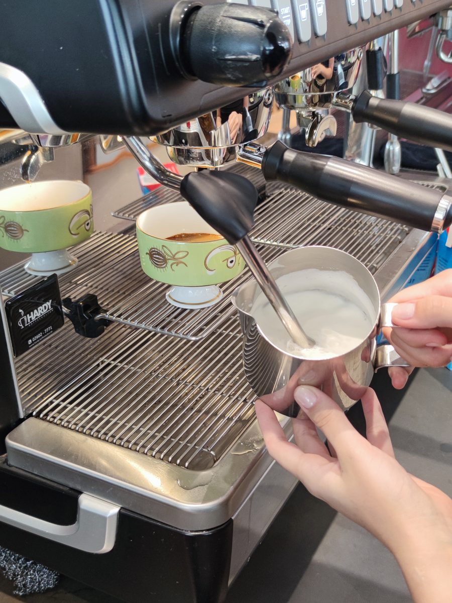 Milch wird an der Espressomaschine aufgeschäumt