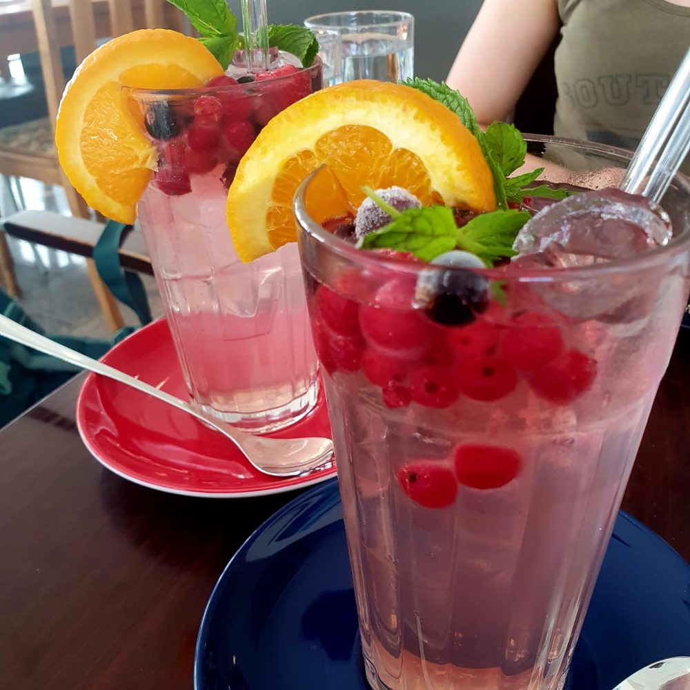 Zwei kalte Sommergetränke mit Beeren und Orange